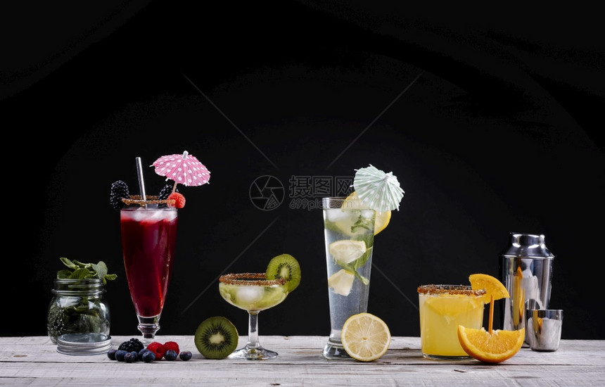 木板和黑底的晶玻璃杯中不同水果的鸡尾酒猕猴桃混合饮食图片