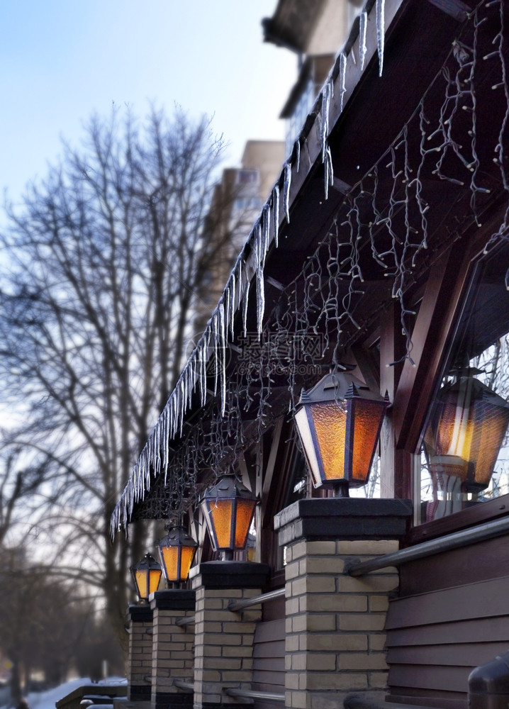 阴凉处视窗象征四座旧街灯在清春晨露天的餐馆窗户旁闪耀着四盏旧街灯它照亮了餐厅前春清晨的光亮街道灯冰向下朝看图片