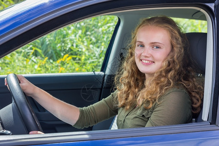 手持方向盘驾驶车轮的荷兰女青年肖像头发成功在后面图片