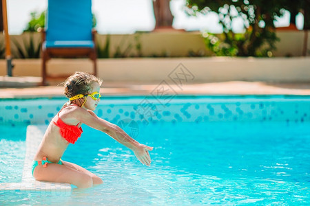 溅在户外游泳池里快乐可爱的小女孩有充气橡皮圈的女孩在豪华酒店的户外游泳池里玩得开心水色泳装背景图片