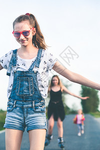 喜悦笑的年轻女孩在夏日共度愉快的滚溜乐趣旱冰鞋背景图片