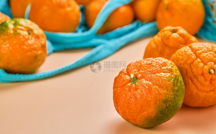 水平的珊瑚板上水果或橘子关闭有选择焦点门达林从一个蓝色邮袋分散到桌子另一侧人们作品图片