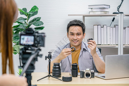 硬件男人营销亚洲Vlogger男子满意每个媒体的相机镜头摄像影机拍视频并用笔记本电脑直播通过社交媒体频道vlog和impactr背景图片