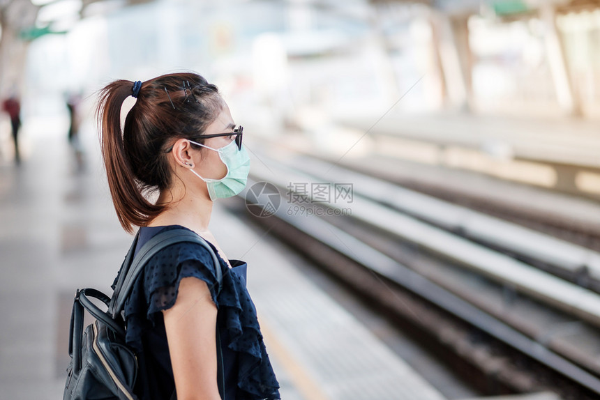 在公共火车站戴口罩的青年女性图片