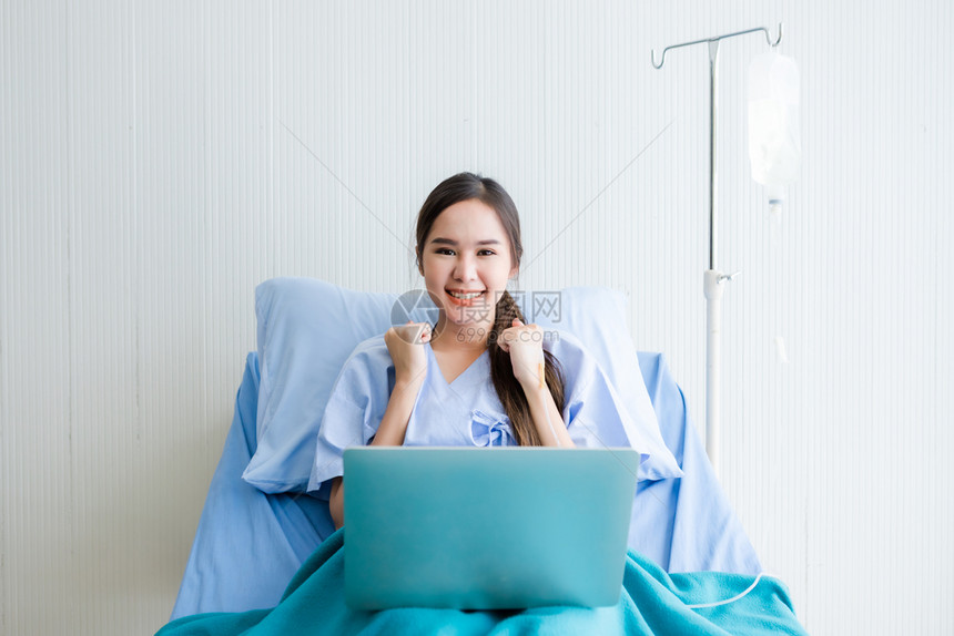 技术疾病一名亚裔年轻女病人在房医院背景的床上和笔记本电脑表示自信认为生病时有工作业务一名年青女病人对床和膝上型计算机充满信心成人图片