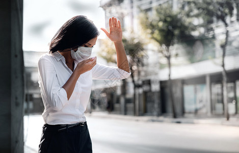 天气在职的流感Covid19或Corona或空气污染PM25情况概念年轻女在公共场合使用医疗面具进行搜捕背景