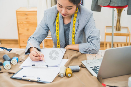 工具女孩在家庭办公室讲习班上工作的有吸引力亚洲时装设计师女时装设计师在家庭办公室工作时尚妇女创造新的布料设计汇编裁缝和纫材料手高清图片素材