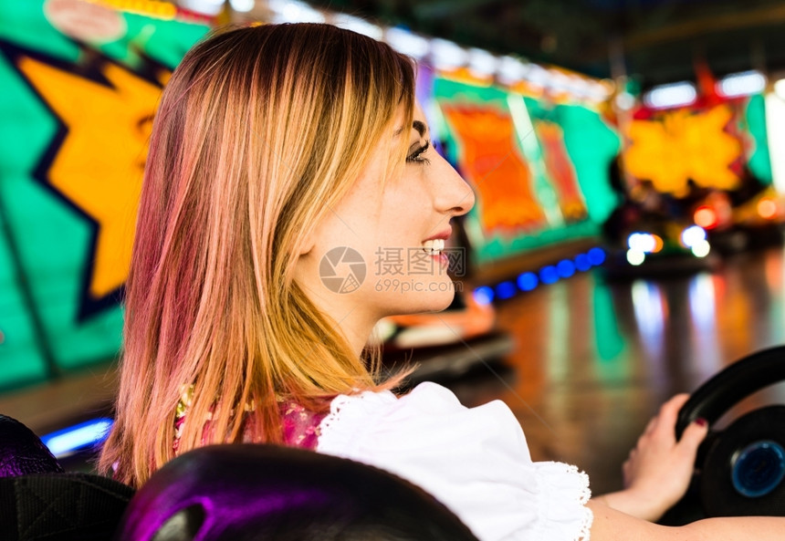 丰富多彩的裙子在娱乐公园的一辆电动面包车中一个美丽的女孩穿着典型德国Dirndl服装在游乐园的一辆电动保险车中背景美丽女孩身穿彩图片