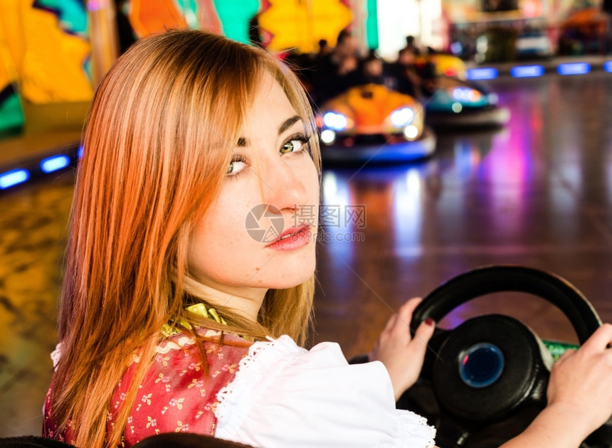 慕尼黑在娱乐公园的一辆电动面包车中一个美丽的女孩穿着典型德国Dirndl服装在游乐园的一辆电动保险车中背景美丽女孩身穿彩色和灯光图片