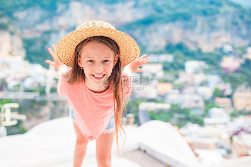 旅游的穿着大草帽小女孩看着意大利波西塔诺镇的摄影机在意大利波西塔诺镇的Amalfi海岸可喜温暖和阳光明媚的夏日历史可爱图片