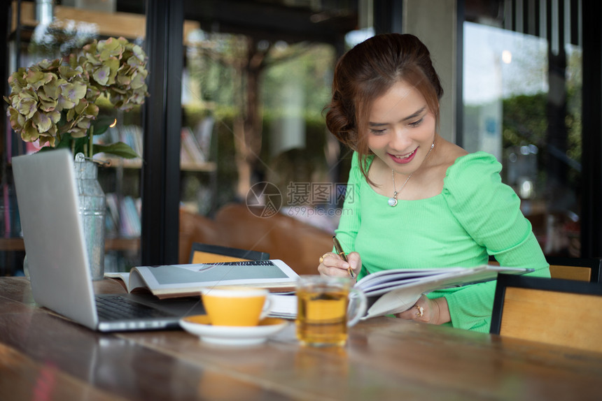 亚洲女企业家微笑并用笔记本进行分析文件和图表财务她正在喝咖啡使用笔记本分析文件和图表金融工作她正在喝咖啡打字闲暇沟通图片