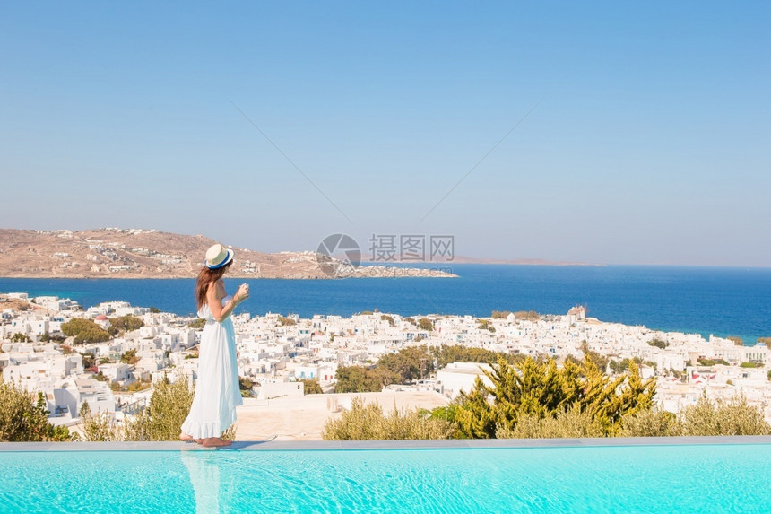 白色的快乐女子在泳池边缘放松与惊人的景色在Mykonos希腊美丽的女享受游泳池附近的暑假旅行松弛图片