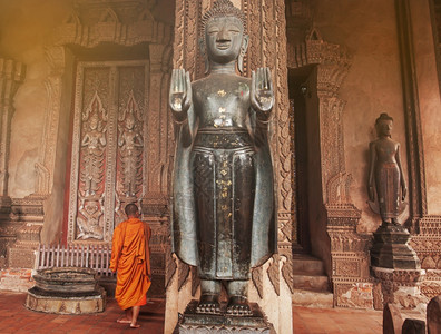 一个和尚挑水喝上市僧古老的HawPhrraKaew的佛教和尚是万象以前的一个寺庙老挝电影铜制青佛面和雕刻门寺庙向公众开放背景