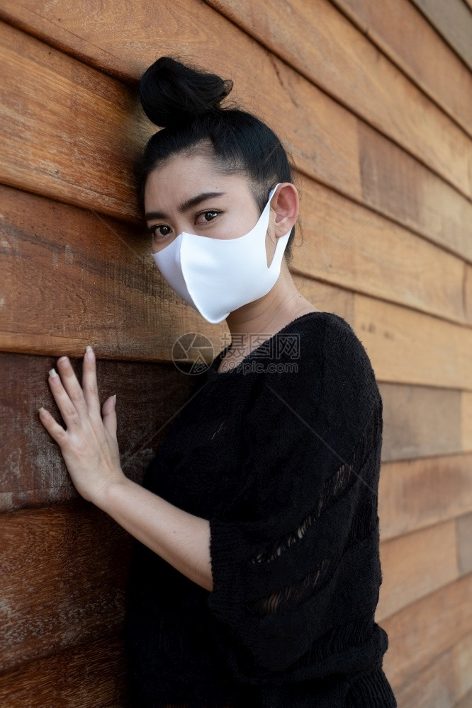 健康紧贴近身的年轻亚洲妇女戴上医疗面具以防止呼吸道疾病如在墙上旧木本底的流感19PM25烟尘和雾请看照相机白种人灰尘图片
