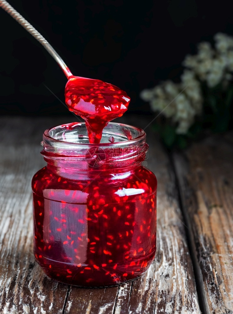 木头准备颜色制桌子上一个玻璃罐里自制的草莓果酱闭着有选择焦点勺子罐上装了果酱有选择焦点勺子从上滴出图片