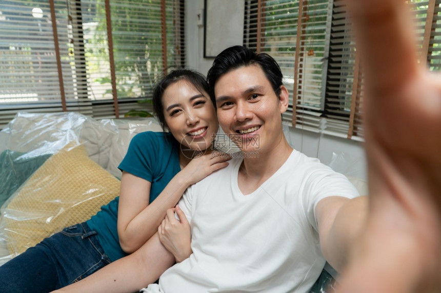 微笑虚拟的亚洲夫妇在第一天搬进新家后与人举行智能手机和电视会议以开始新生活为目的搬迁和转置概念AC54970联系图片