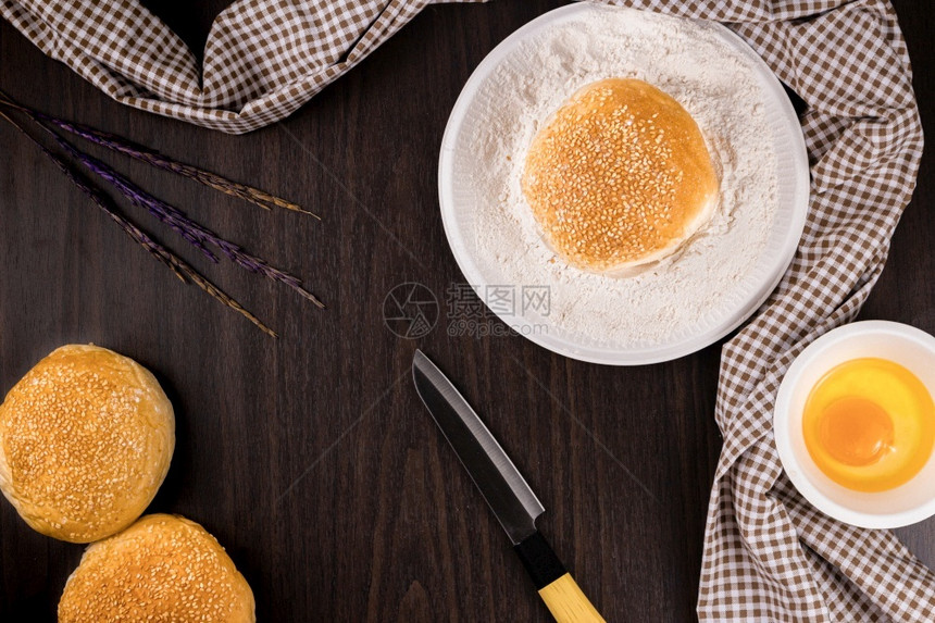 滚动面包店概念一碗面粉把刀和碗小生鸡蛋放在黑木桌上制的图片