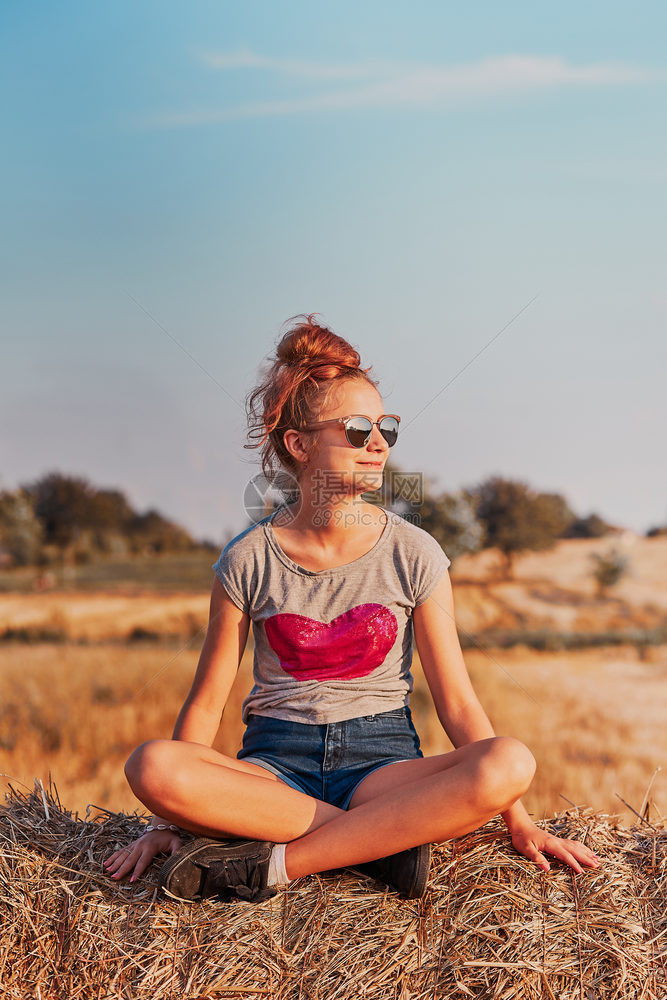 农村心业快乐笑的少女坐在日落时的干草树上享受在乡下Candid人的暑假真实时刻情况图片