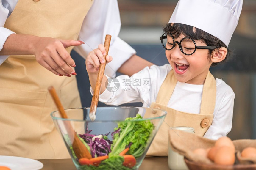 感兴趣的成人爱做饭亚洲小可爱男孩在家庭厨房里和妈一起做饭很滑稽人们的生活方式和家庭自制食物原料概念两个泰国人制作了由水生食物沙拉图片