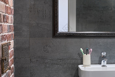 灯光内部详细信息中灰色瓷石器砖墙和水槽上方的镜子时髦浴室内个人卫生用品气氛下沉背景图片