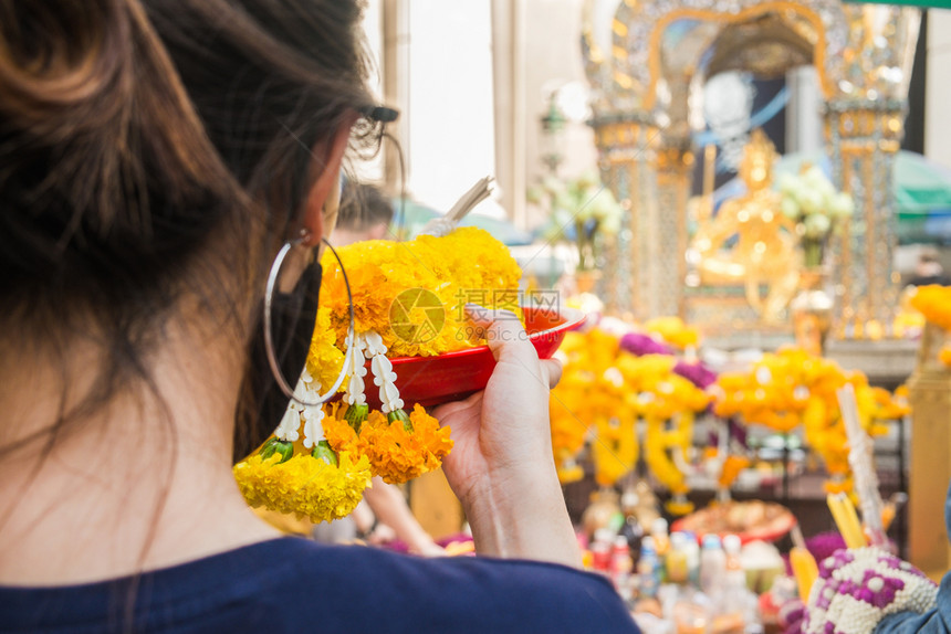 一名妇女用泰国曼谷Erawan神社的花草园做礼仪祭式户外愿望图片