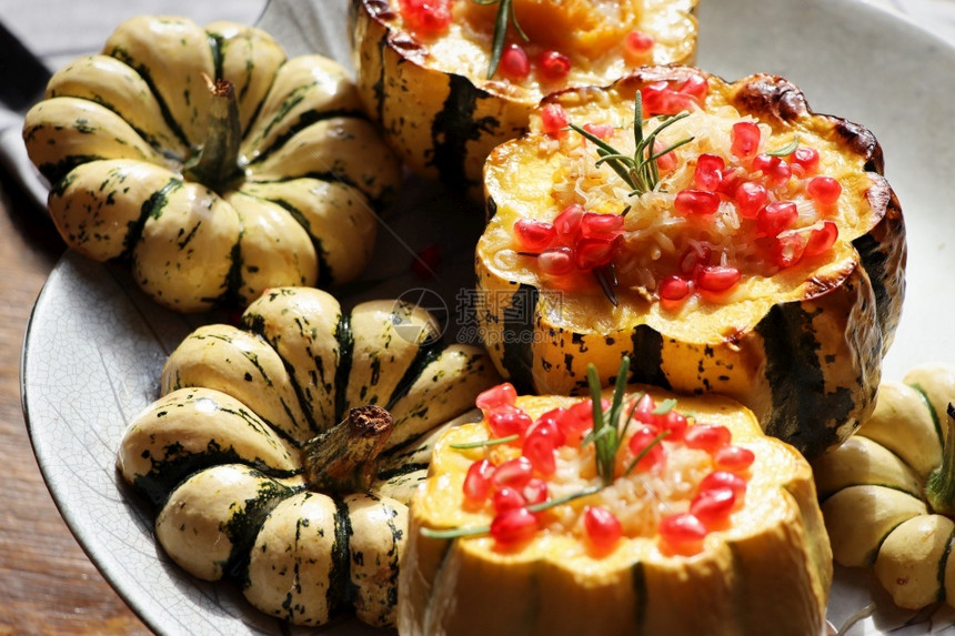 炖胡萝卜壁球南瓜烩饭放在空心南瓜中烤配奶酪和石榴籽选择焦点南瓜烩饭放在空心南瓜中图片