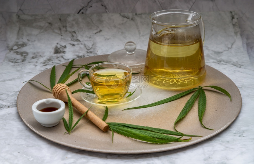 清新和享受一杯草药茶和一杯绿树叶理石桌上有蜂蜜的绿色叶以及理石桌上的蜂蜜以医疗为目的用于睡眠和焦虑草药茶健康饮料概念睡觉美丽的研图片