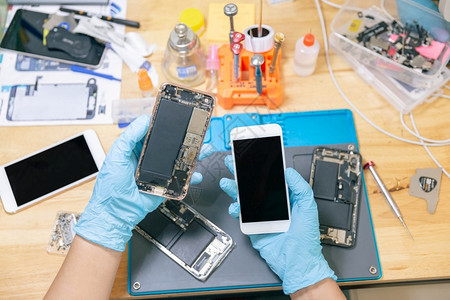 维修工拆卸损坏的智能手机组件图片
