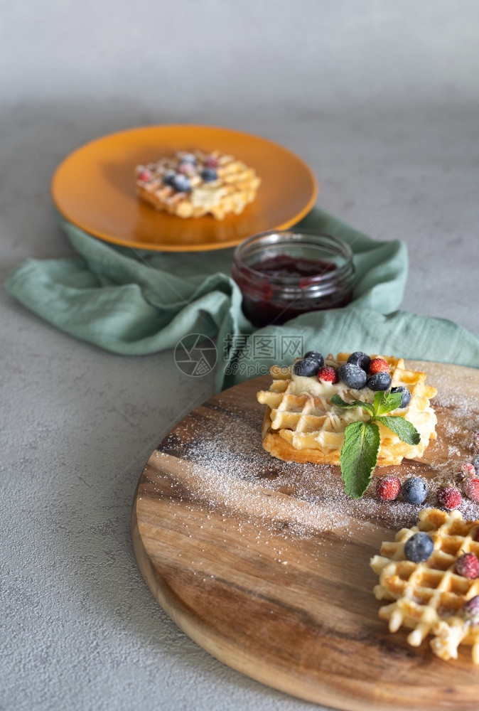 奶油圆木砍板装满华芙饼盛草莓果酱和蓝以及软背景的薄荷和蓝莓面包店圆形的图片