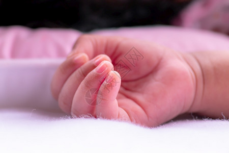 白色的为人父母婴儿手躺在白毛干净的布衣上新出生3周健康的女婴手把合的照片翻起来手指是如此小和可爱的粉色睡美容概念图象学步的儿童背景图片
