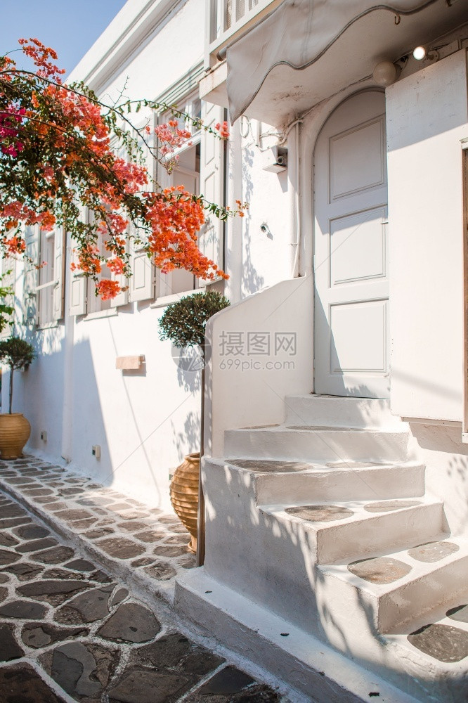 游客脚步希腊美丽村庄的狭窄街道带蓝色阳台楼梯白色房屋和鲜花希腊语图片
