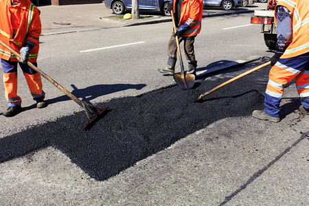 大队委摄影铲筑路工作队在部分道路上堆放新鲜沥青并平整以便在道路施工中进行维修人大队在道路施工中用铁锹清理部分沥青碎石背景