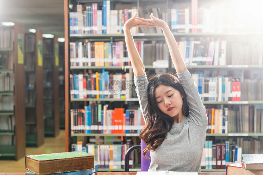 各种样的在大学图书馆或群落里阅读和做功课的亚洲青年学生在书架上木制桌子的各种书籍和文具上写着返回学校的书架知识人们图片
