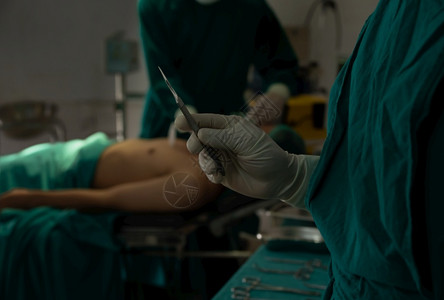 男人团队合作一种关闭外科医生的手和疗乳胶套将术刀放在医院室内操作以及图片