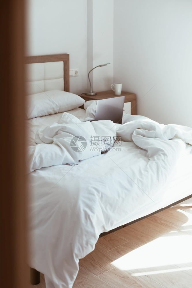 卧室现代公寓有阳光和最起码的设计在大流行病中保持安全在无人制床铺舒适和的偏远家用办公室使手提式电脑现代化公寓提供日光和最起码的设图片