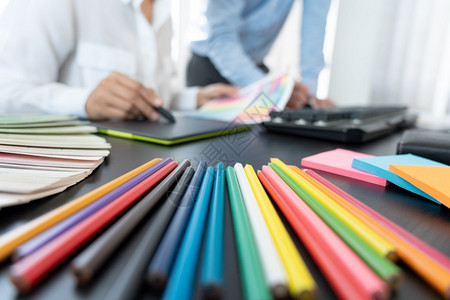 工作座牌素材20多岁女商人使用彩色观察编辑艺术作品的图片设计小组在创意办公室工作在桌上用平板牌和图案编辑白种人背景