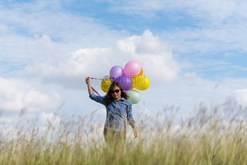 裙子女人拿着气球在绿色草地白云和蓝天空上奔跑快乐轻松的天空手拿着充满活力的空气球在生日派对上欢快的盛宴玩保持蓝色的图片