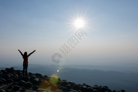 轮廓旋钮夏天日落时站在山顶悬崖上的年轻女子休光月亮享受着对空石头地自然观的看法PhuHinRinRongKla公园山悬崖上的领导背景图片