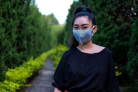 冷清户外科青年亚洲妇女站立并戴上面罩以防止像公园中的流感灰尘和烟雾一样的呼吸道疾病防止感染空气中呼吸道疾病妇女安全感染概念背景图片