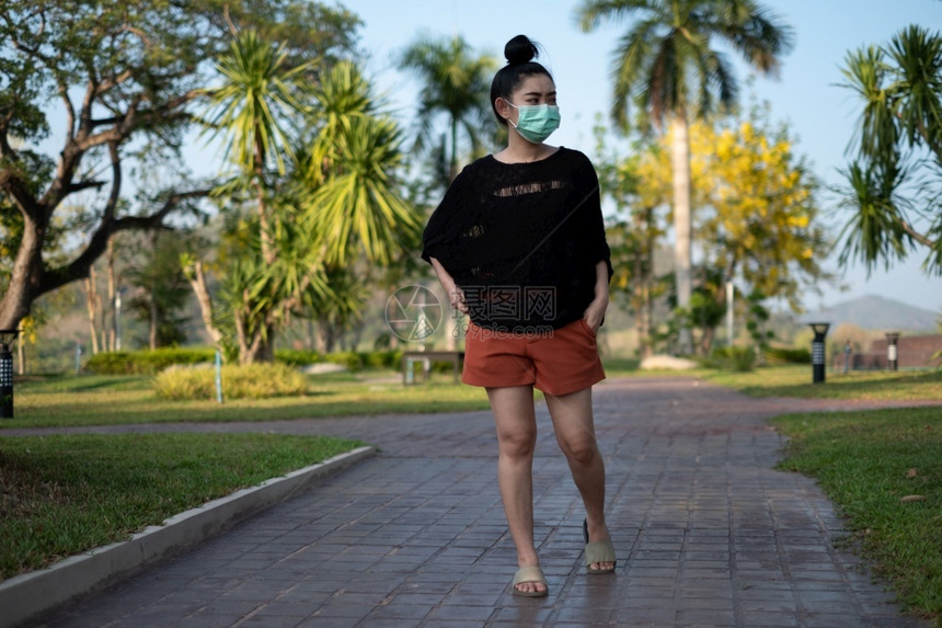 模型青年亚洲妇女站立并戴上医疗面具以防止像公园中的流感尘和烟雾一样的呼吸道疾病妇女安全毒感染概念防止传染呼吸道疾病女孩健康图片