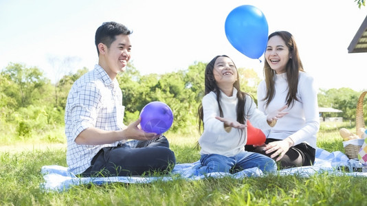 人与气球素材野餐女孩积极的亚洲家庭肖像父亲和母与女儿的亚洲家庭出亲之旅享受放松与家人一起玩气球以自由生活方式家庭假期康卡西亚人节日旅行新诺尔背景