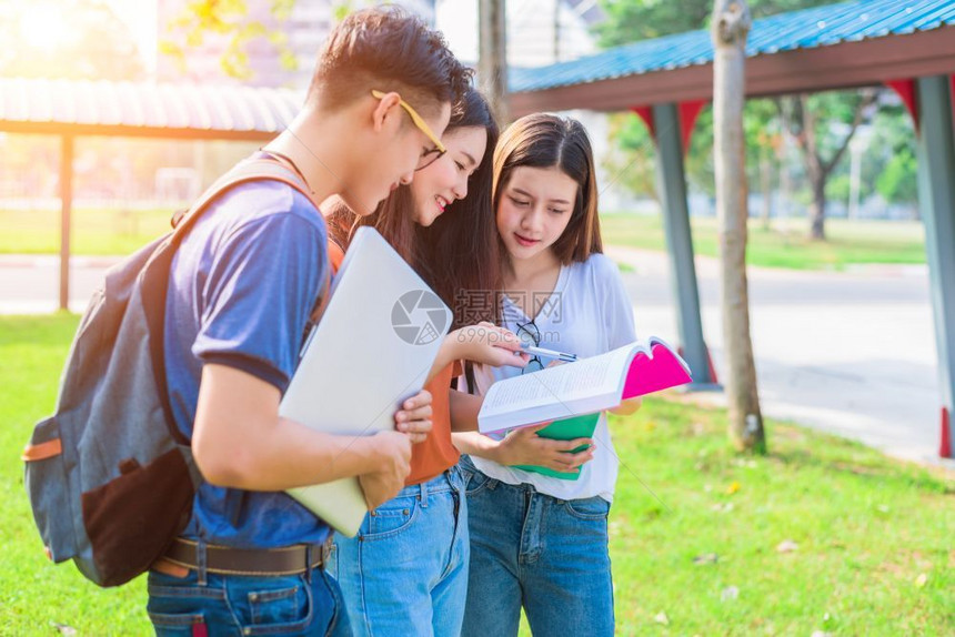 三名学生一起在草地上讨论图片