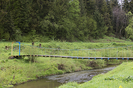 在树林中挂着一座悬吊桥横跨山河高上的悬浮桥在明亮的绿林喀尔巴阡山脉乌克兰森林中挂着悬吊桥跨越山河穿过越木头水平的背景图片