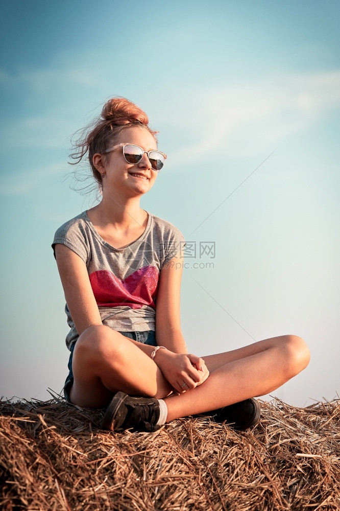 女孩坐在干草地上享受乡村的暑假康迪德人真实的时刻情况笑声季节坦率户外图片