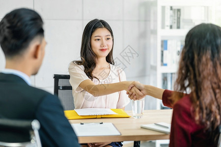 行政人员年轻亚洲女毕业生与两名经理握手在开始面试前欢迎两位经理在会议室进行积极动的工作面试Business雇用新会员Job面试第背景图片