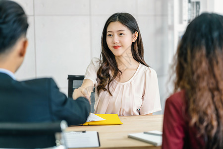 JOB办公室成功的就业年轻亚洲女毕生与两名经理握手在开始面试前欢迎两位经理在会议室进行积极动的工作面试Business雇用新会员Job背景