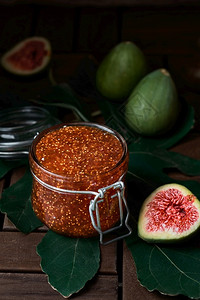 如图在玻璃罐子里的Fig果酱旁边是半个新的无花果特接器准备秋季水果甜点深木背景垂直框架有选择的焦点秋天健康图片