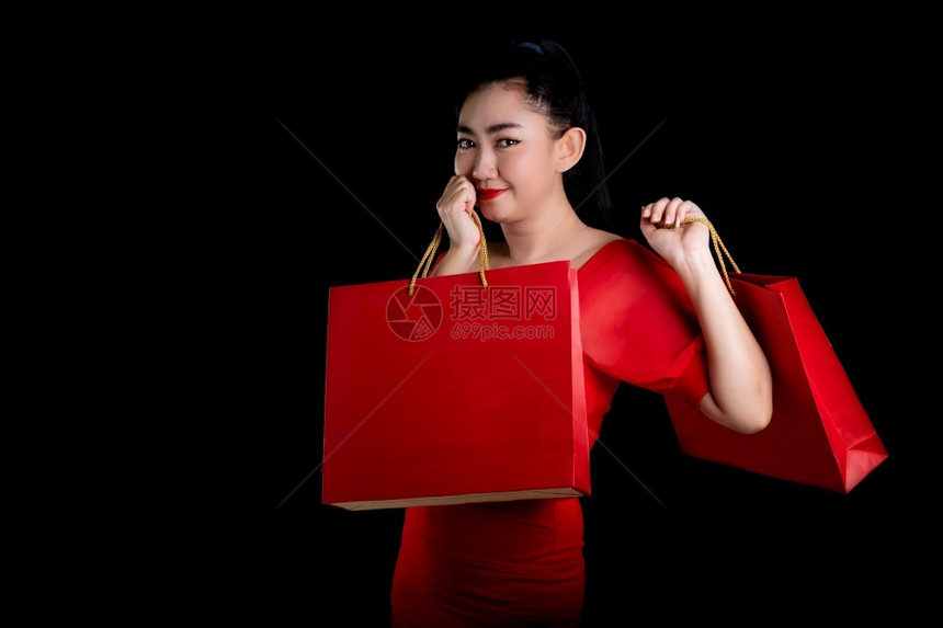 手一位美丽的亚洲年轻女身着红色礼服持有信用卡和购物袋的黑背景销售概念照相机等被描绘成肖像卡片看图片