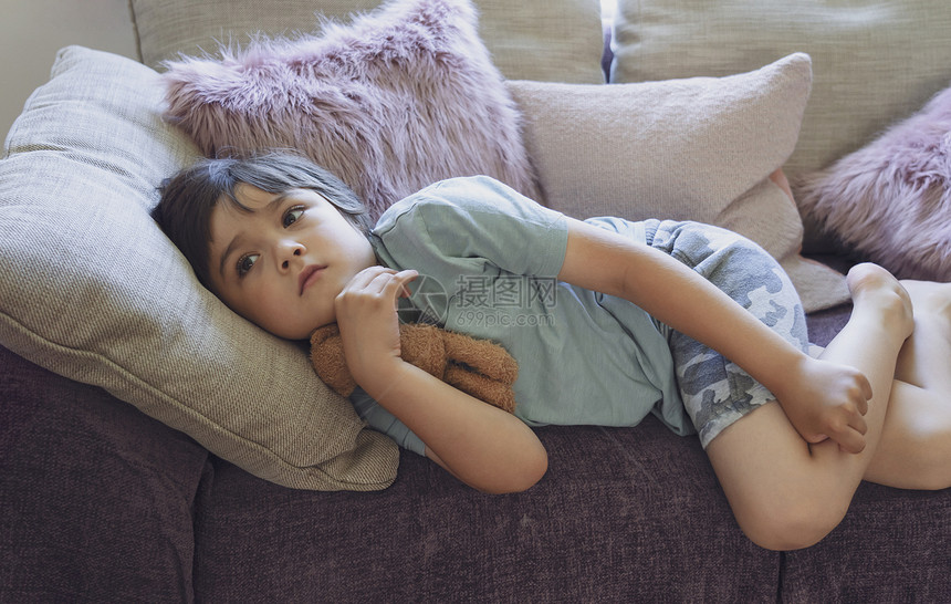 关心甜的年轻快乐男孩在沙发上躺毛绒枕头喜悦的孩子们看电视周末在家放松暖和舒适的场景图片