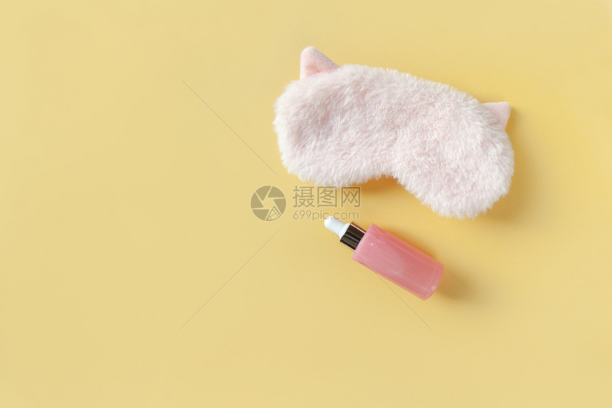 粉毛的睡面具小耳朵和瓶子面朝用血清在纸黄背景上生动梦想和皮肤护理概念模仿空间水平关心行业松弛图片